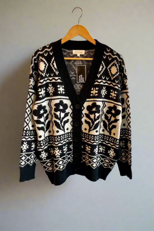 Black cardigan with white and beige floral pattern on a hanger against a white background