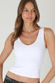Woman wearing a white tank top against a plain background
