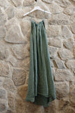Green dress hanging on a hanger against a stone wall