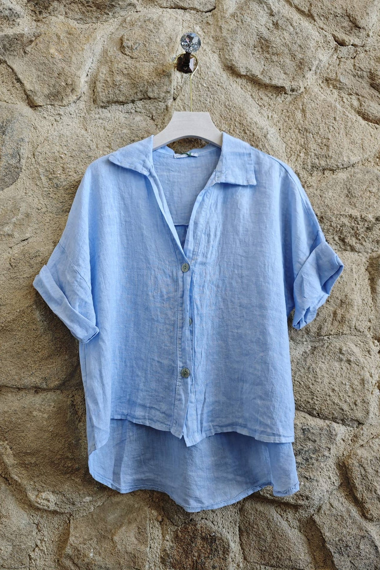 Light blue shirt on a hanger against a textured stone wall