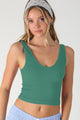 Woman wearing a green tank top and blue pants with a white background