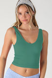 Woman wearing a green tank top and blue pants with a white background