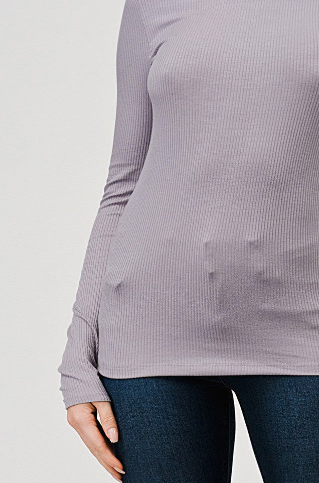 Woman wearing a gray ribbed turtleneck sweater against a plain background