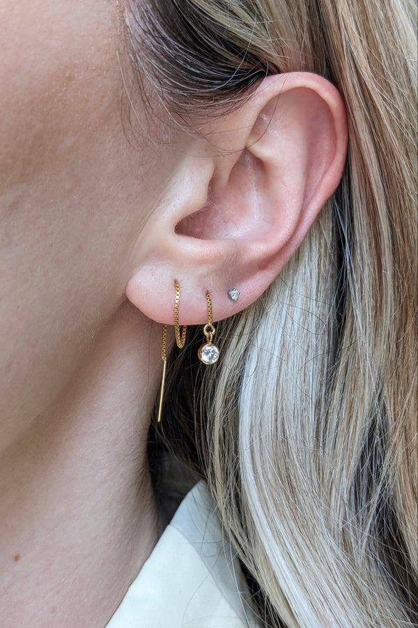 Close-up of an ear wearing gold hoop earrings with a blurred background
