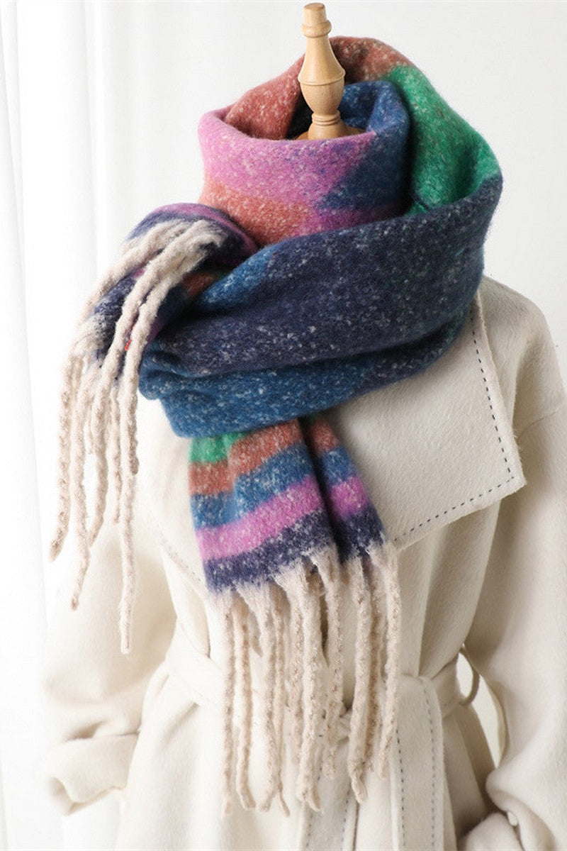 Multicolored striped scarf with tassels draped over a white coat on a mannequin against a white background.