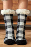 Black and white checkered socks with fluffy cuffs on a wooden floor.