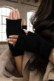 Person wearing black fingerless gloves with a beige background