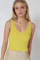 Woman wearing a yellow tank top and floral skirt on a white background