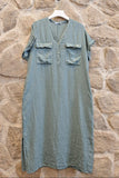 Green dress on a hanger against a stone wall