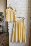 Yellow striped top and skirt set hanging on a brick wall.