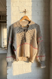 Knitted sweater with a geometric pattern hanging on a brick wall.