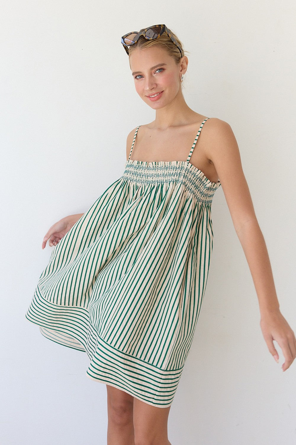 Woman wearing a green and white striped dress against a plain background