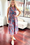 Woman in a floral dress standing in a room with large windows.