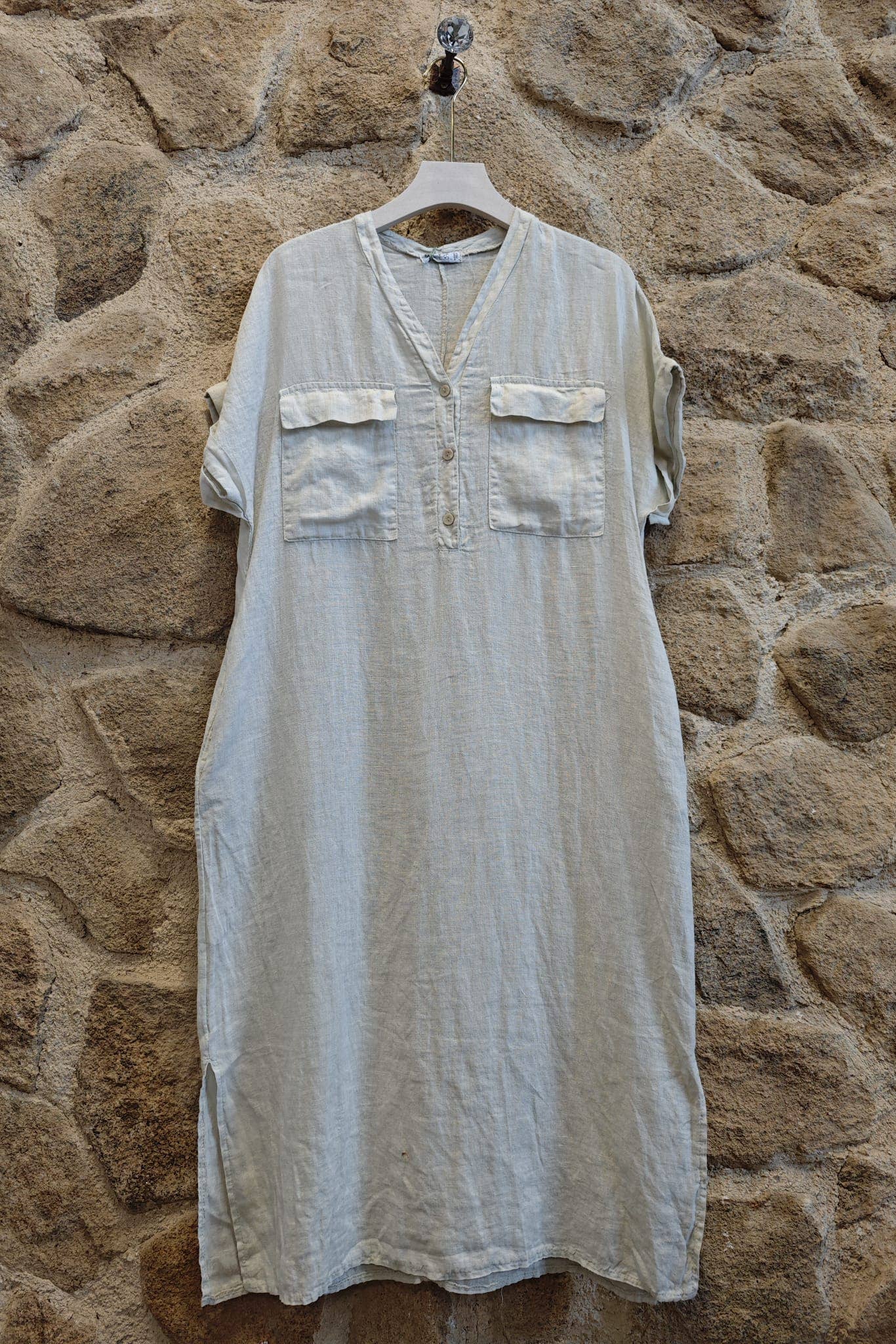 Light-colored dress on a hanger against a stone wall