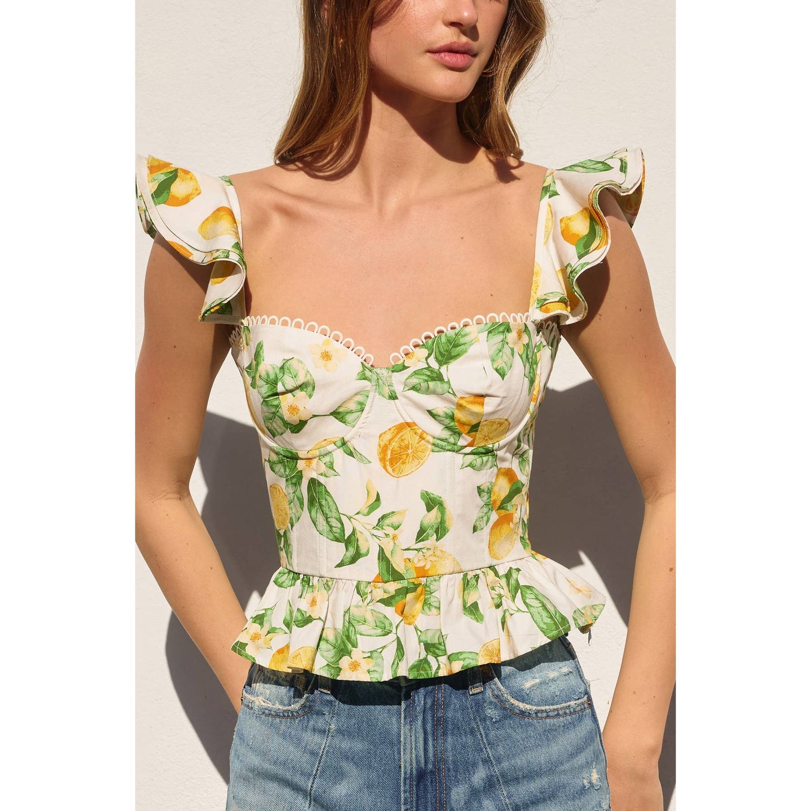 Woman wearing a floral top with lemon design against a neutral background