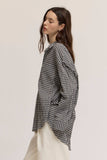 Woman wearing a black and white checkered shirt and white pants on a plain background