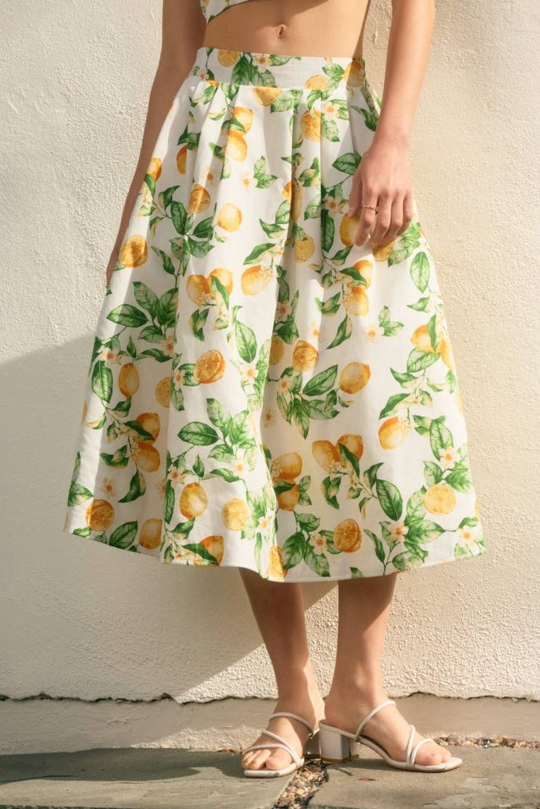 Person wearing a lemon print dress against a neutral wall.
