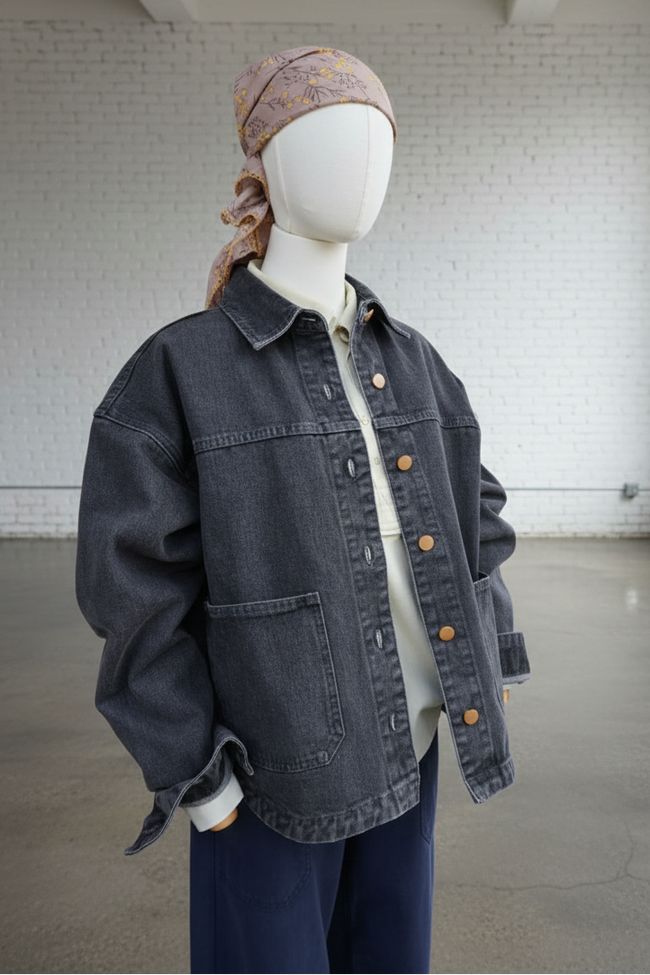 Mannequin wearing a dark denim jacket and headscarf in an indoor setting with white brick walls.