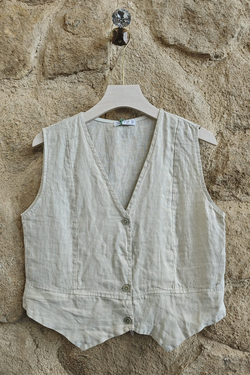 Beige vest on a hanger against a stone wall