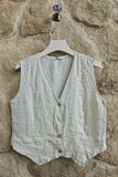 Beige vest on a hanger against a stone wall
