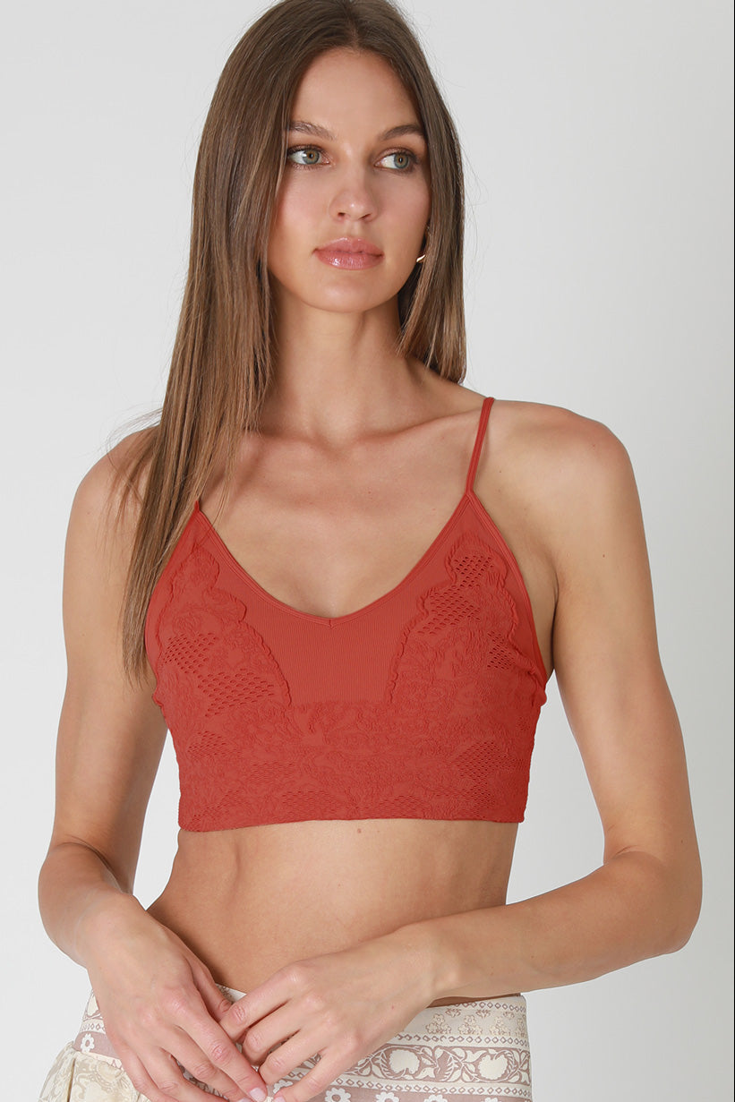 Woman wearing a red lace top on a plain background