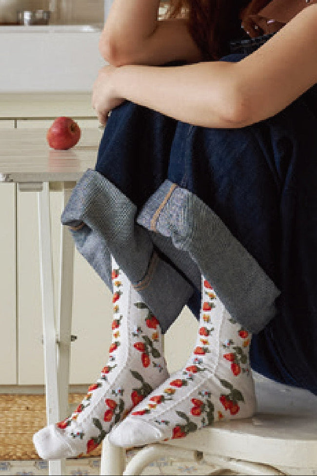 Person sitting on a chair wearing floral socks with strawberry
 design