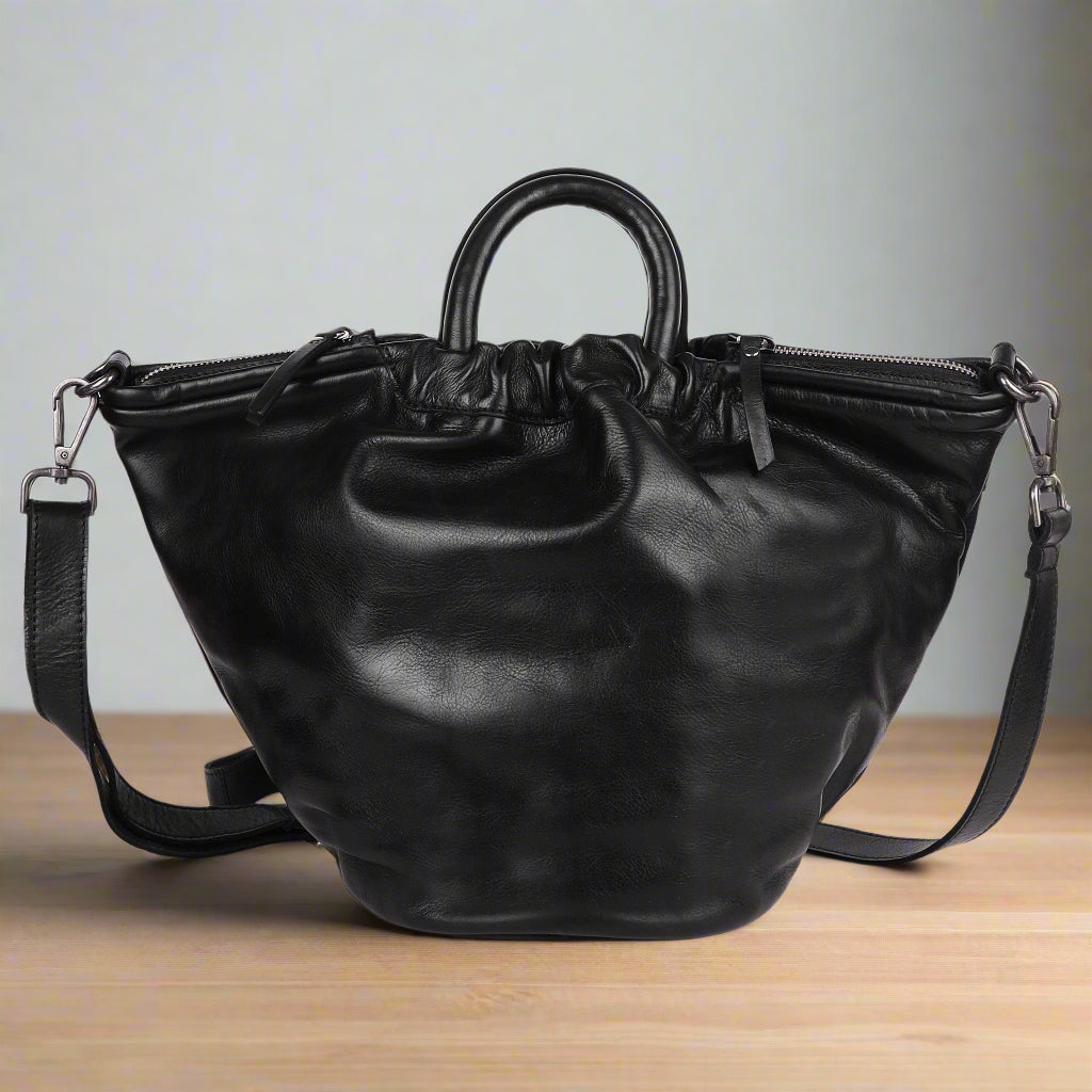 Black leather handbag with a shoulder strap on a white background