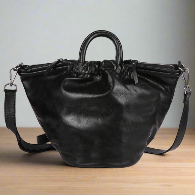 Black leather handbag with a shoulder strap on a white background
