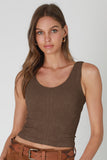 Woman wearing a brown tank top and brown pants on a plain background