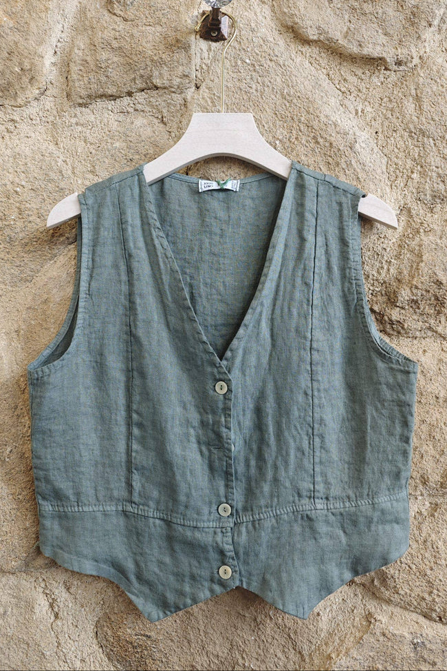 Green vest on a hanger against a stone wall