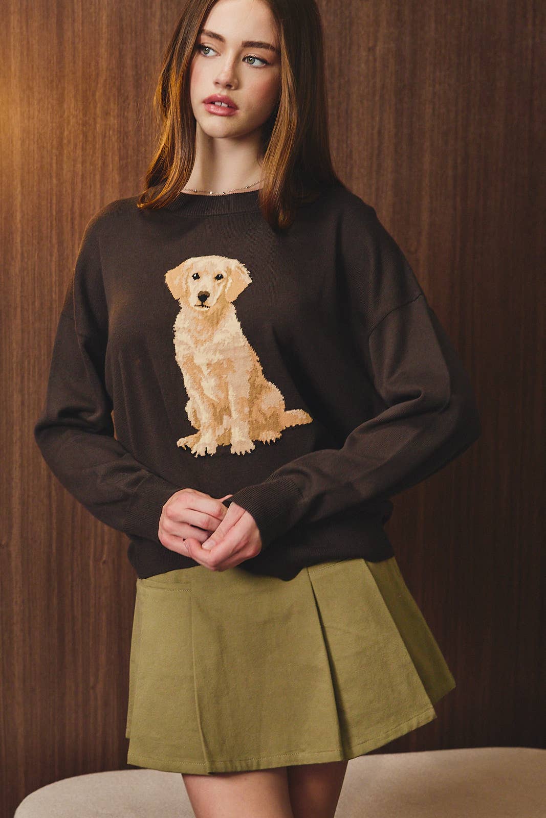 Woman wearing a black sweater with a dog graphic against a wooden background