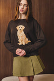 Woman wearing a black sweater with a dog graphic against a wooden background