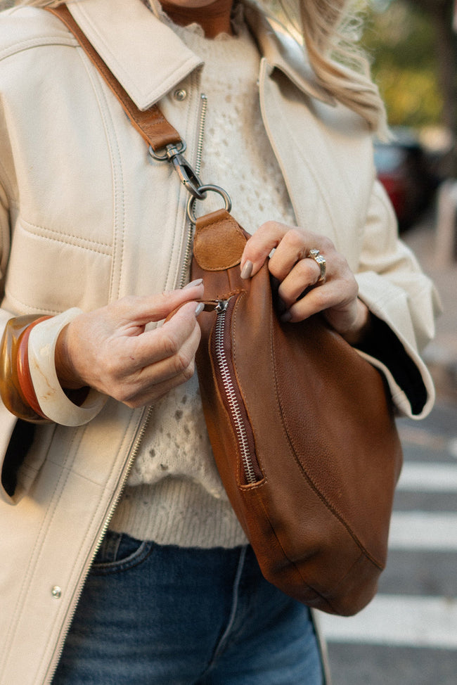 Person holding a brown leather bag on a city street