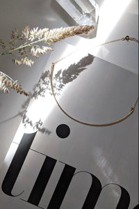 Gold necklace on a white surface with 'JIN' branding