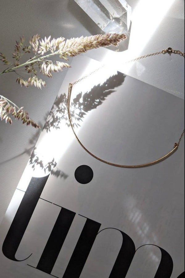 Gold necklace on a white surface with 'JIN' branding