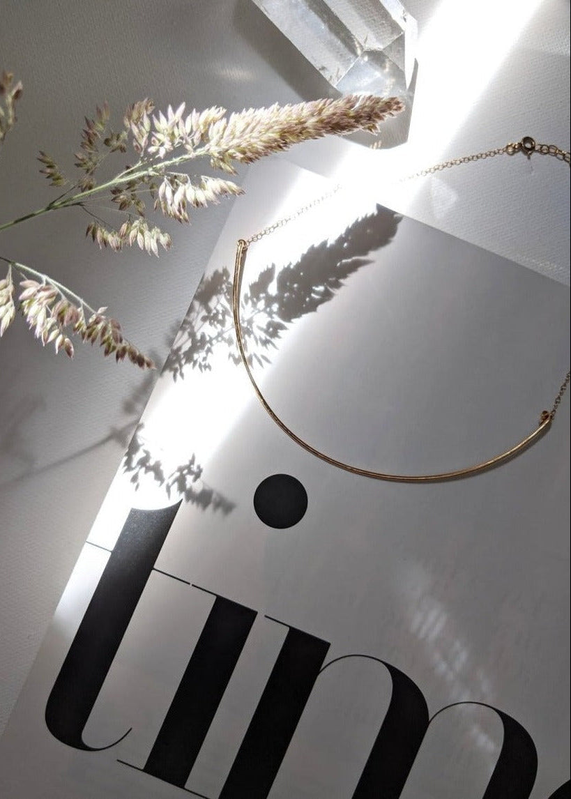 Gold necklace on a white surface with 'JIN' branding