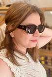 A person wearing bold rectangular polarized sunglasses with a black frame.