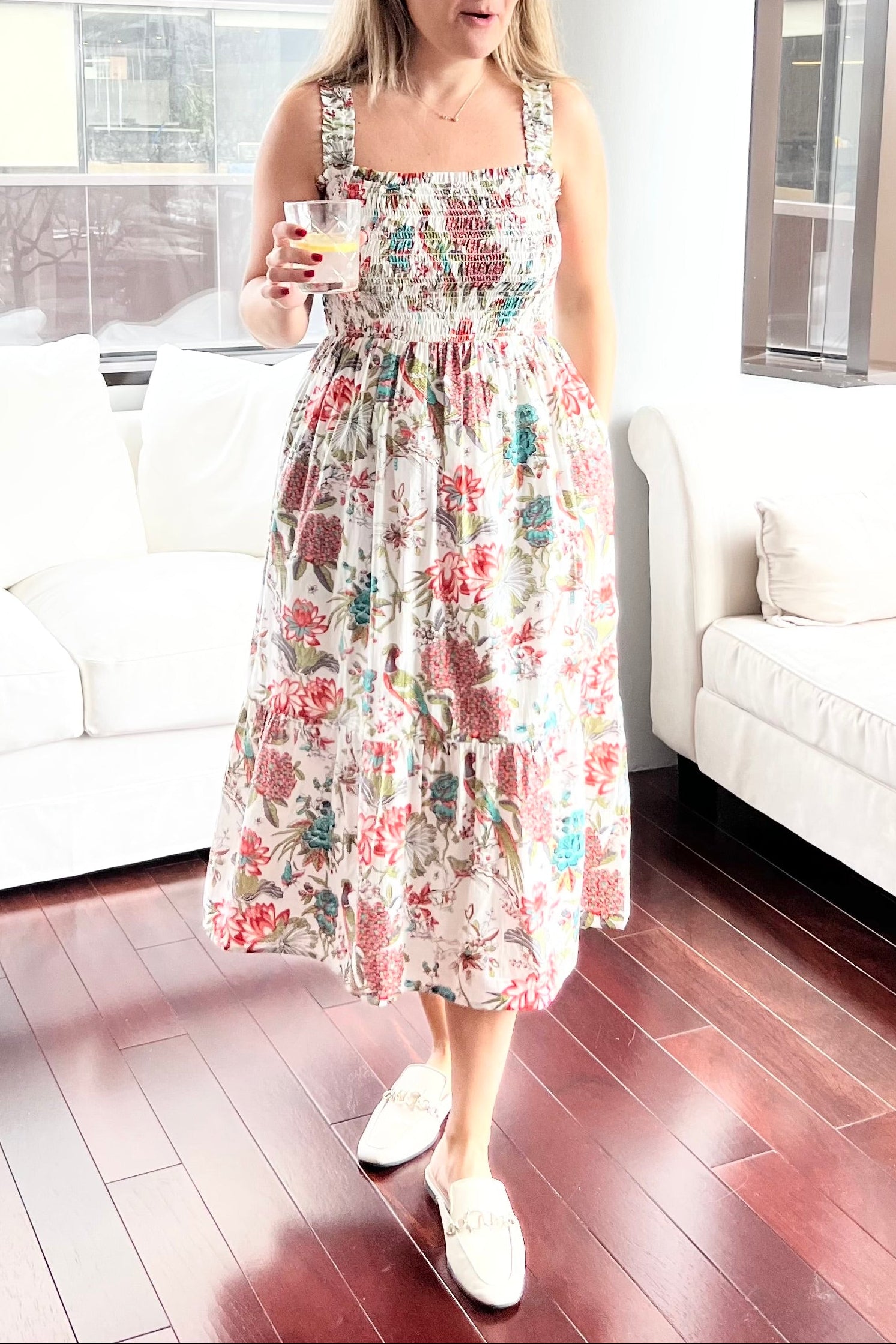 Woman in a floral dress standing in a modern living room.