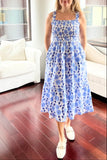 Woman in a blue floral dress standing in a modern living room.