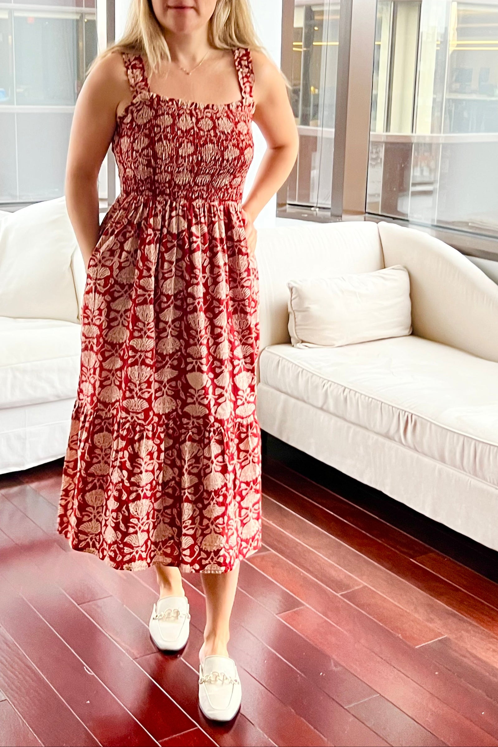 Woman in a red floral dress standing in a modern living room.