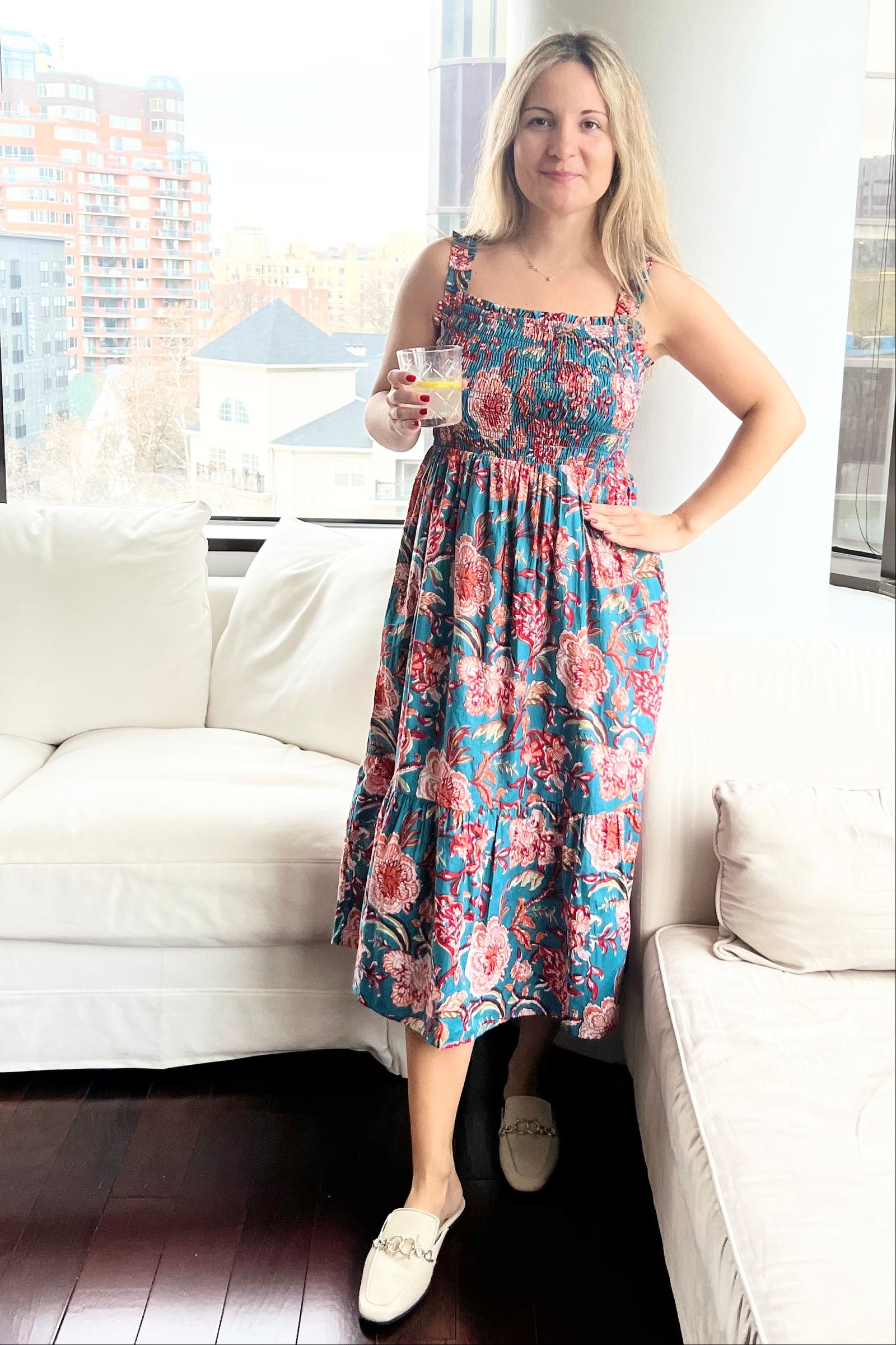 Woman in a floral dress standing in a modern living room.