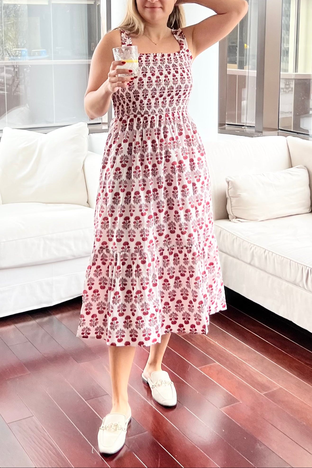 Woman in a patterned dress standing in a modern living room.