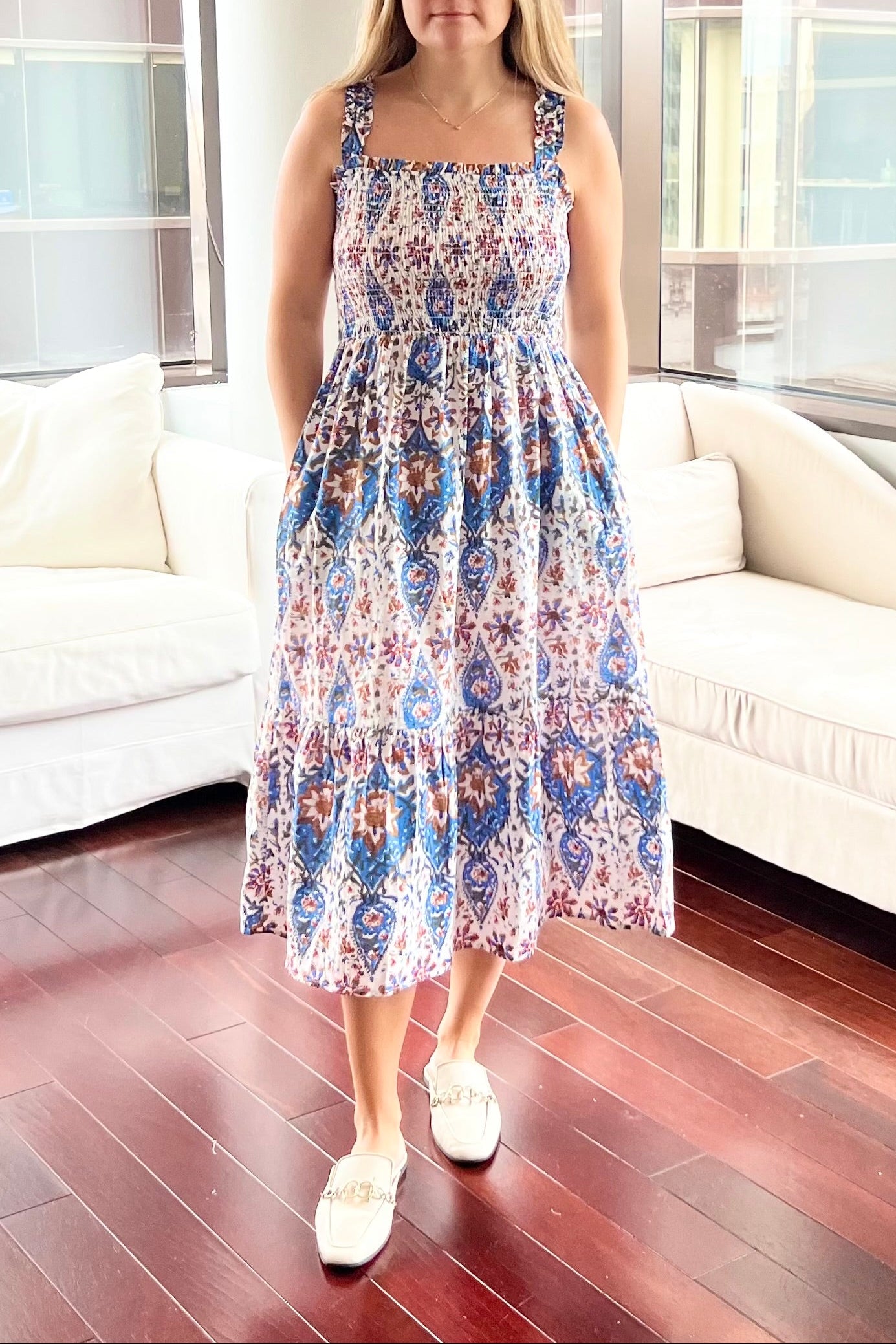 Woman in a floral dress standing in a modern living room.
