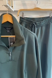 Green half-zip sweatshirt and pants on hangers with tags attached.