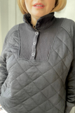 Person wearing a black quilted pullover with a white background
