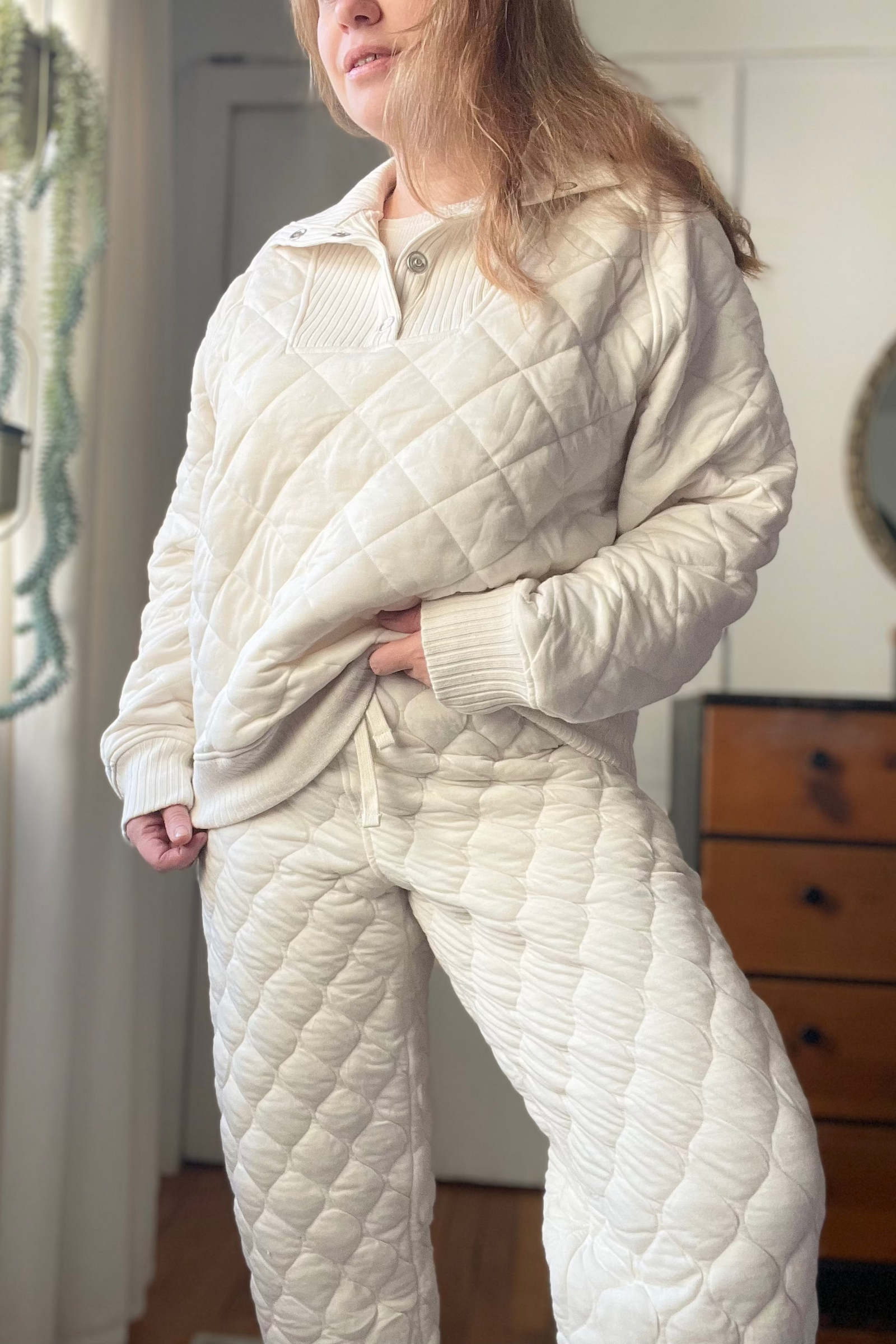 Person wearing a quilted white pajama set in a room with a dresser and mirror.