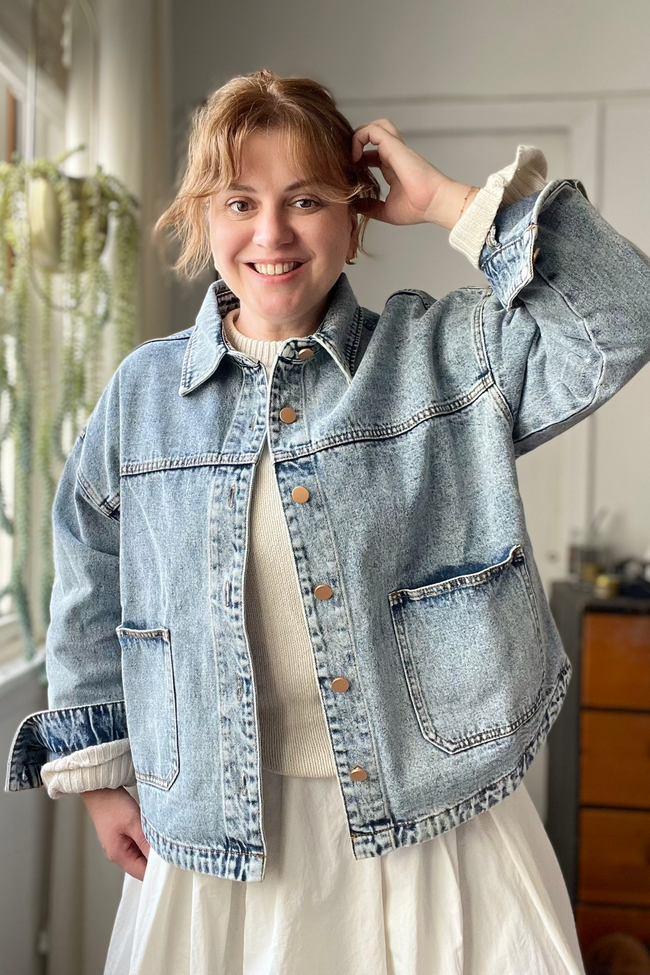 Person wearing a denim jacket indoors with a neutral background