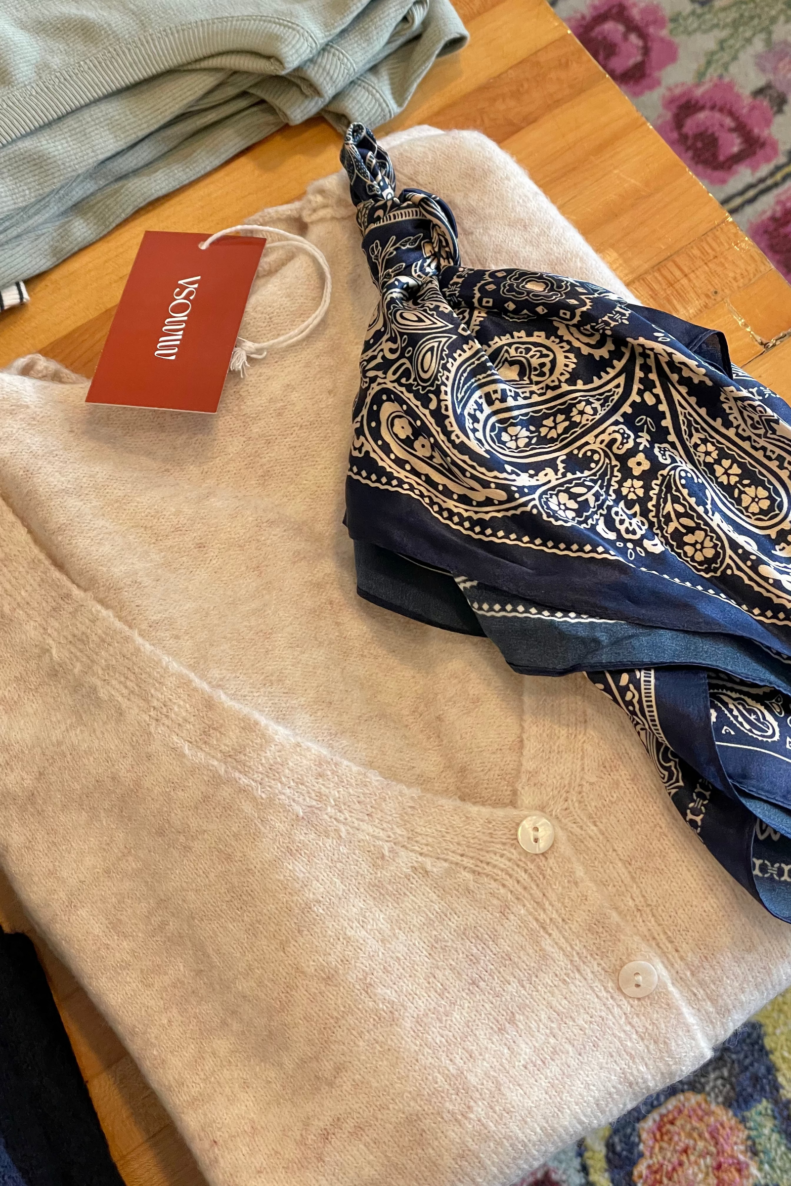 Beige cardigan with a patterned blue scarf on a wooden surface
