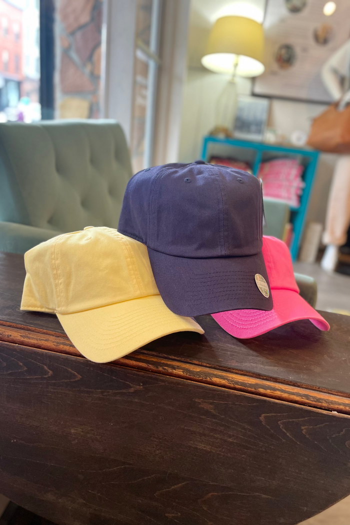 Three colorful baseball caps on a wooden surface with a blurred indoor background.