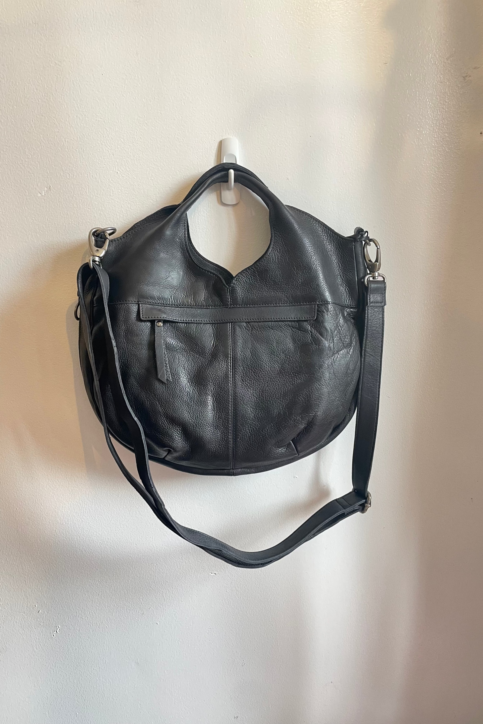 Black leather handbag with a strap on a beige background